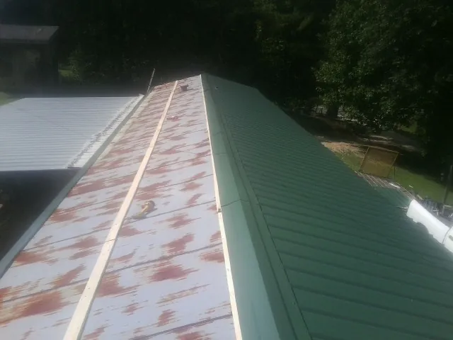 Old rusted panels beside newly installed green metal roofing — Wind Damage Roof Repair by Roofing Brothers in San Angelo