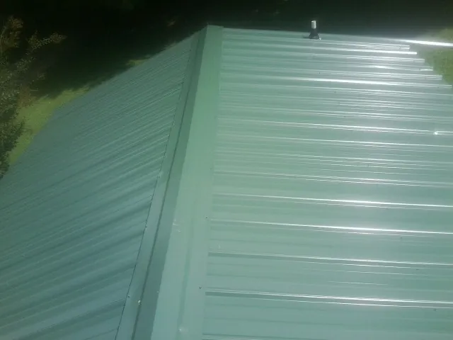 New green metal panels meeting at the ridge of a roof — Flat Roof Repair work by our crew in San Angelo