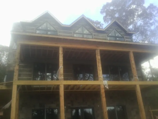 Dormers and porch framing on a large log home under construction — Roof Coating work by our crew in San Angelo