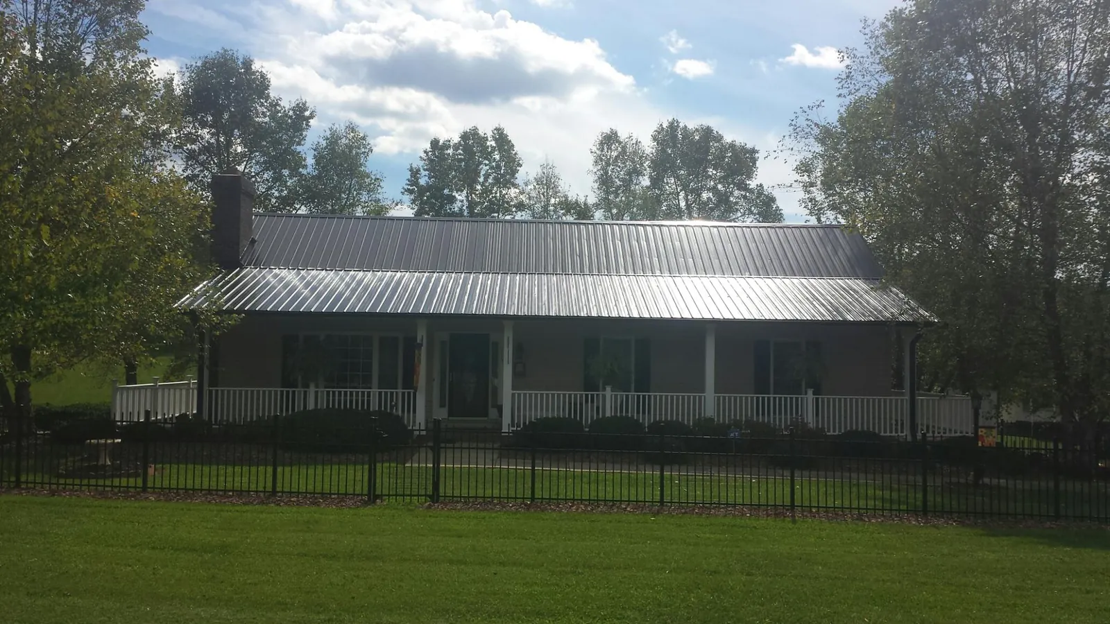 Gray metal roof on a brick ranch with a full width front porch — Gutter Guard Installation work by our crew in San Angelo