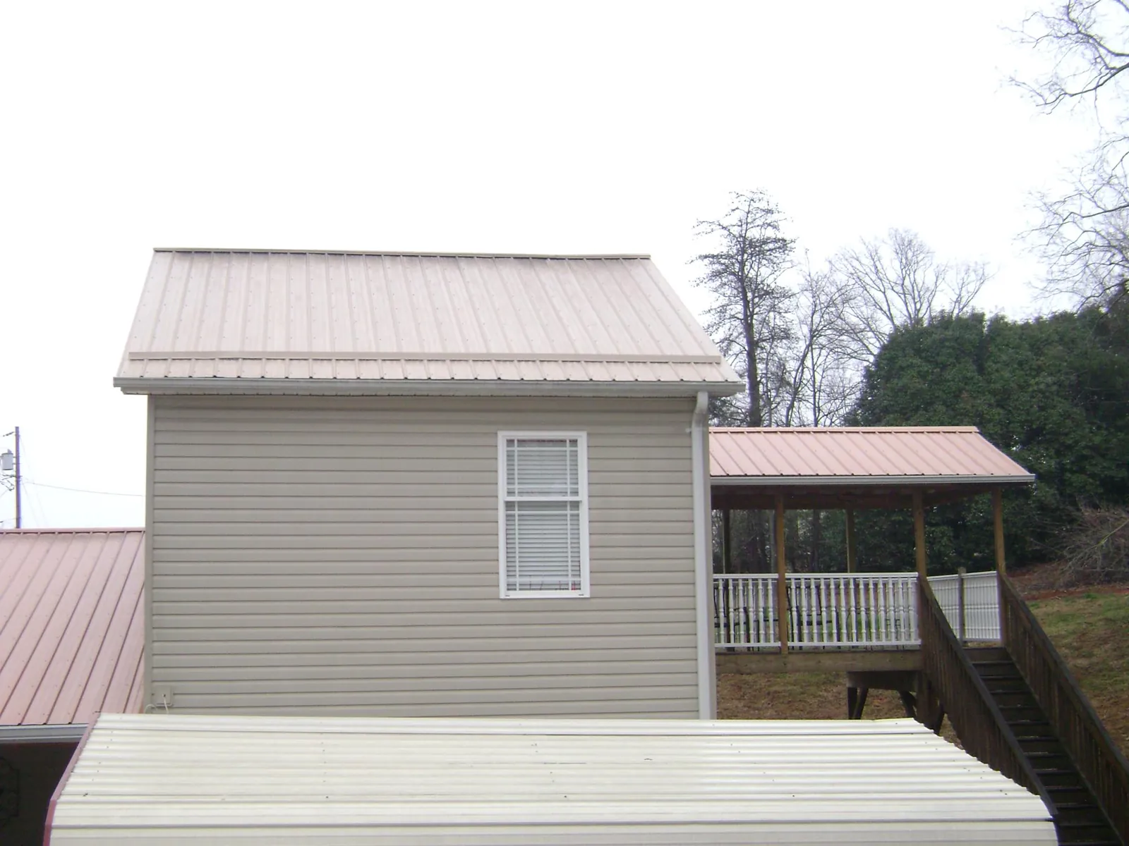 Tan metal roofs on a two story addition and attached porch, from a Roof Replacement job in San Angelo